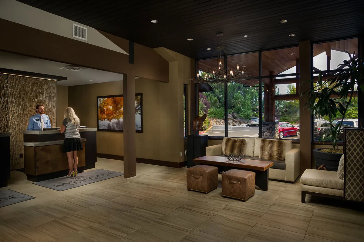 This image features a reception area with a comfortable seating arrangement, large windows that let in natural light, and tasteful artwork on the walls. The space is tidy and welcoming, suggesting a high standard of housekeeping and care for guests.