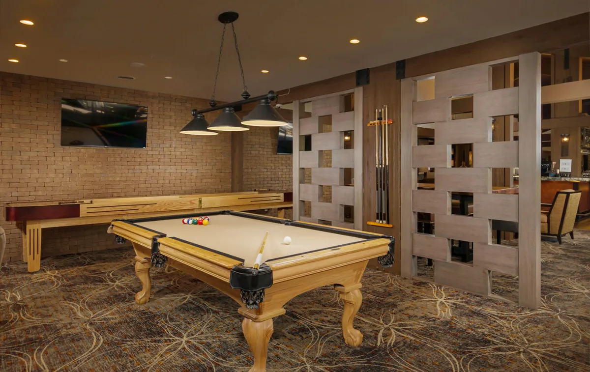 A modern recreation area with a pool table, stylish hanging light fixtures, and a wooden partition for a sense of privacy. The mood is relaxed and playful, offering a space to unwind after a busy workday.